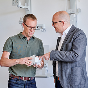 Mitarbeiter zeigt Kunde ein Produktteil Mitarbeiter zeigt Kunde ein Produktteil