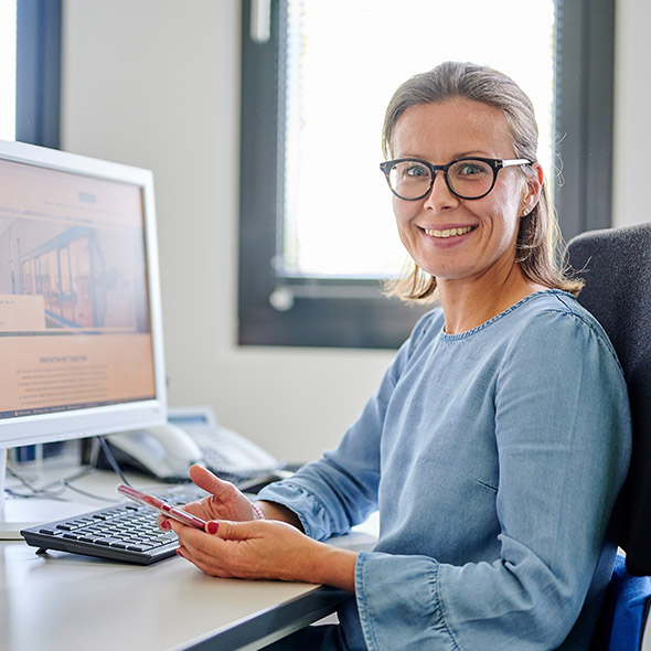 Eine Frau mit Brille sitzt am Schreibtisch vor einem Computer Eine Frau mit Brille sitzt am Schreibtisch vor einem Computer